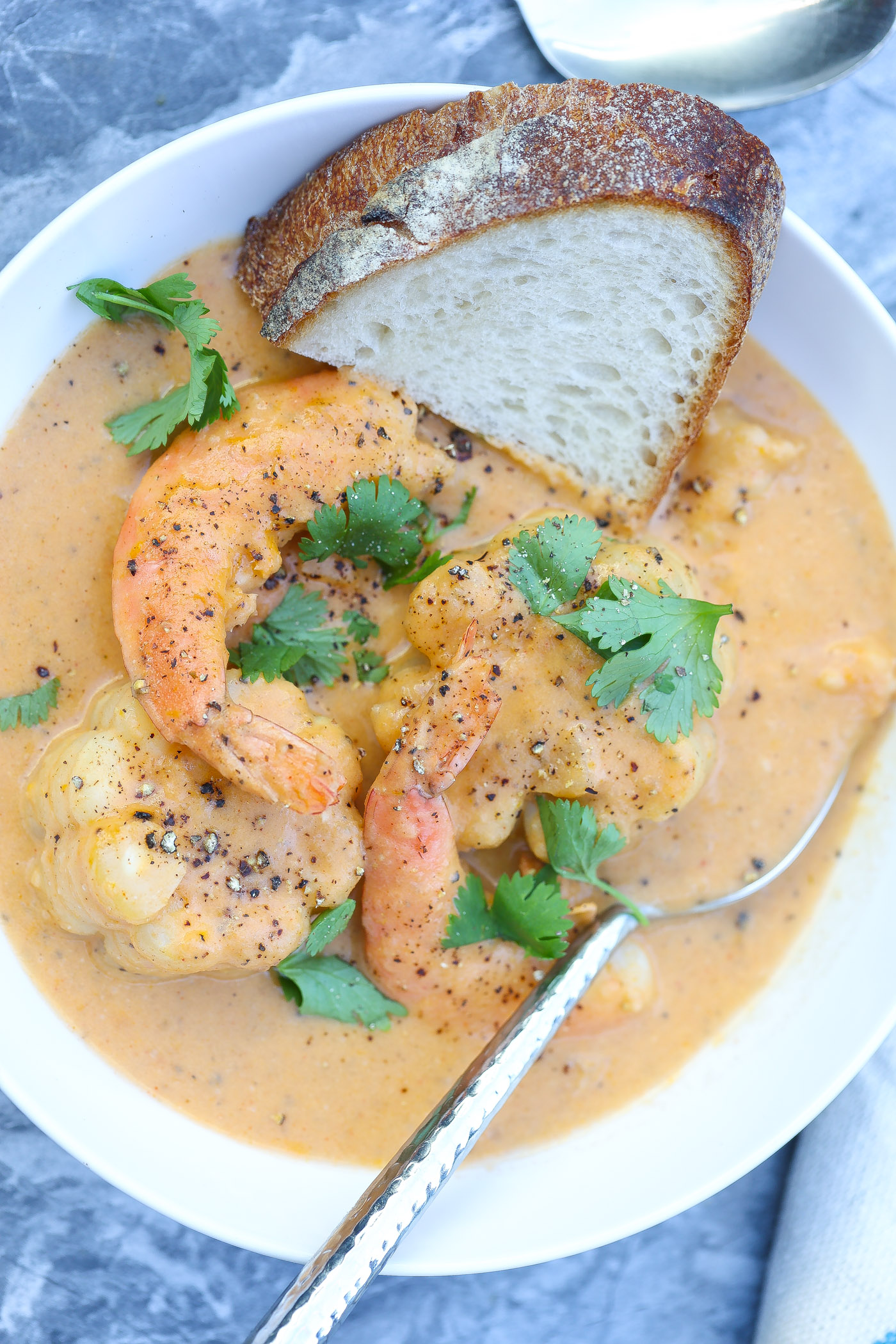 shrimp and corn in a white bowl with bread slice