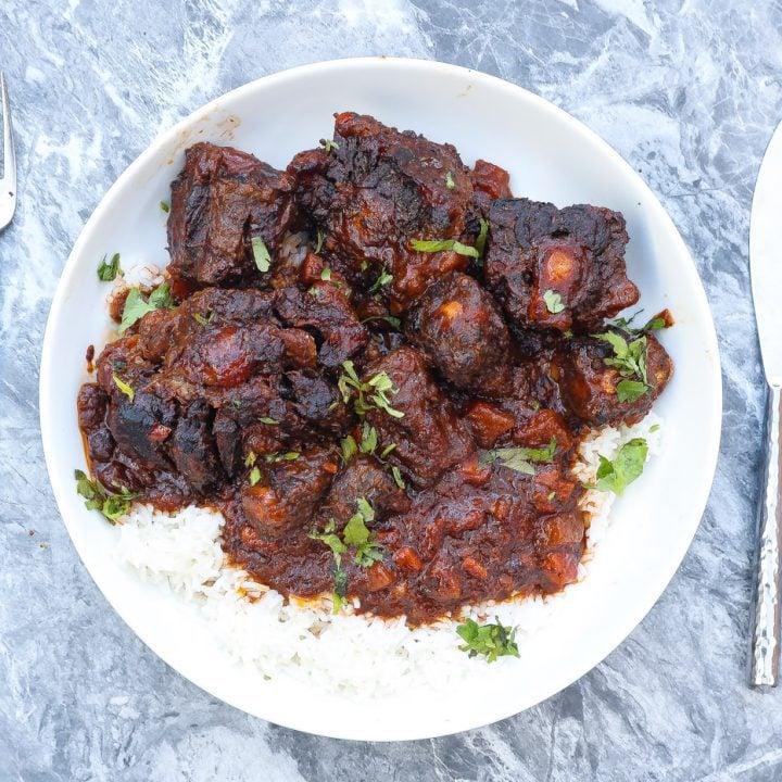 oxtails, gravy, and rice in white bowl