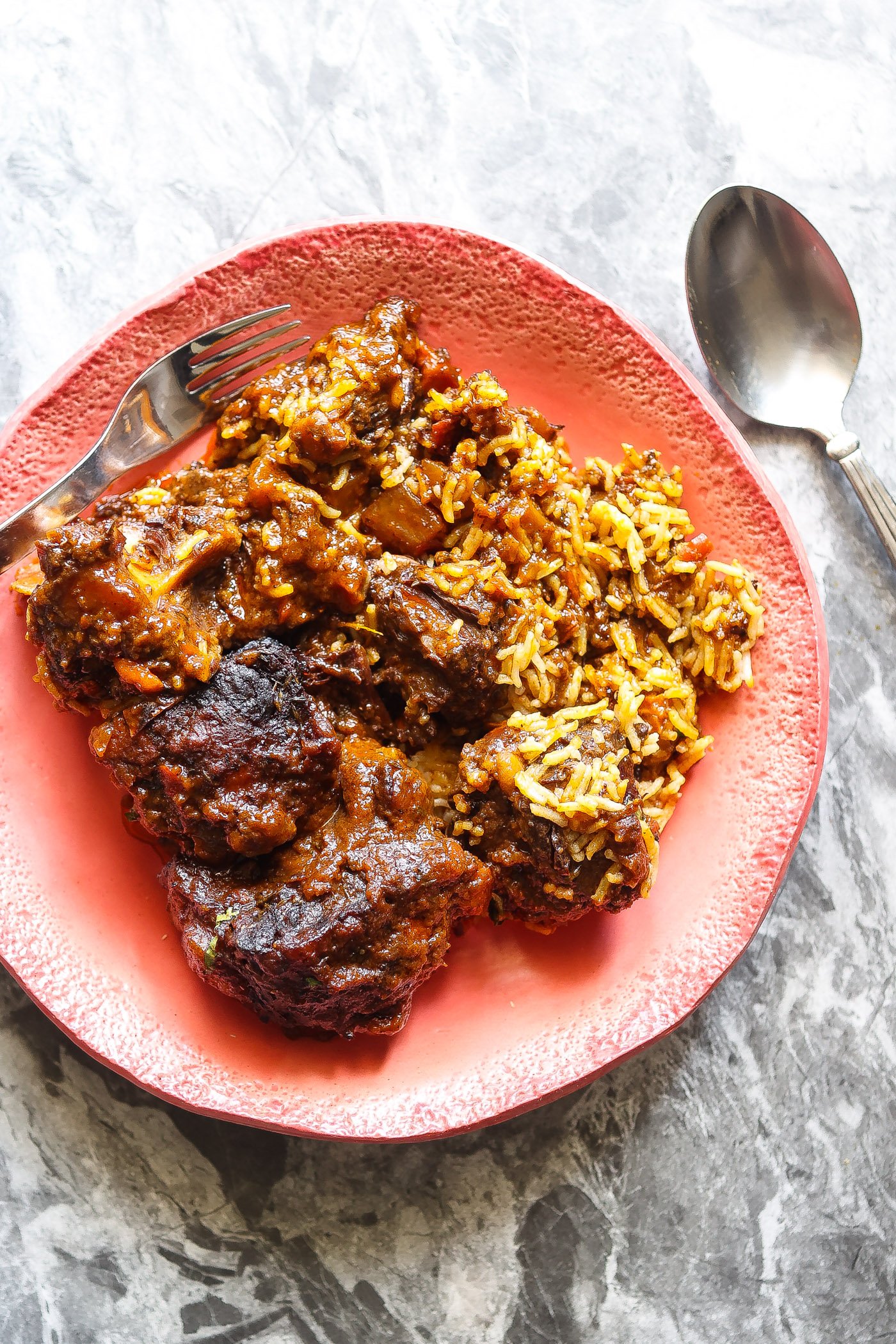 oxtails, gravy, and rice in pink bowl