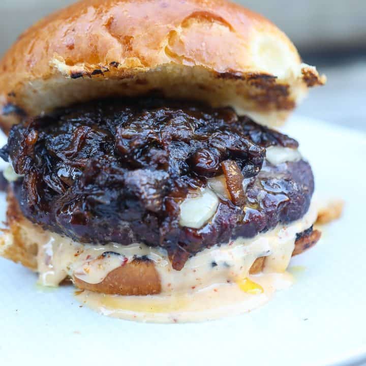 smoked burger with melted cheese, sauce, and caramelized onions