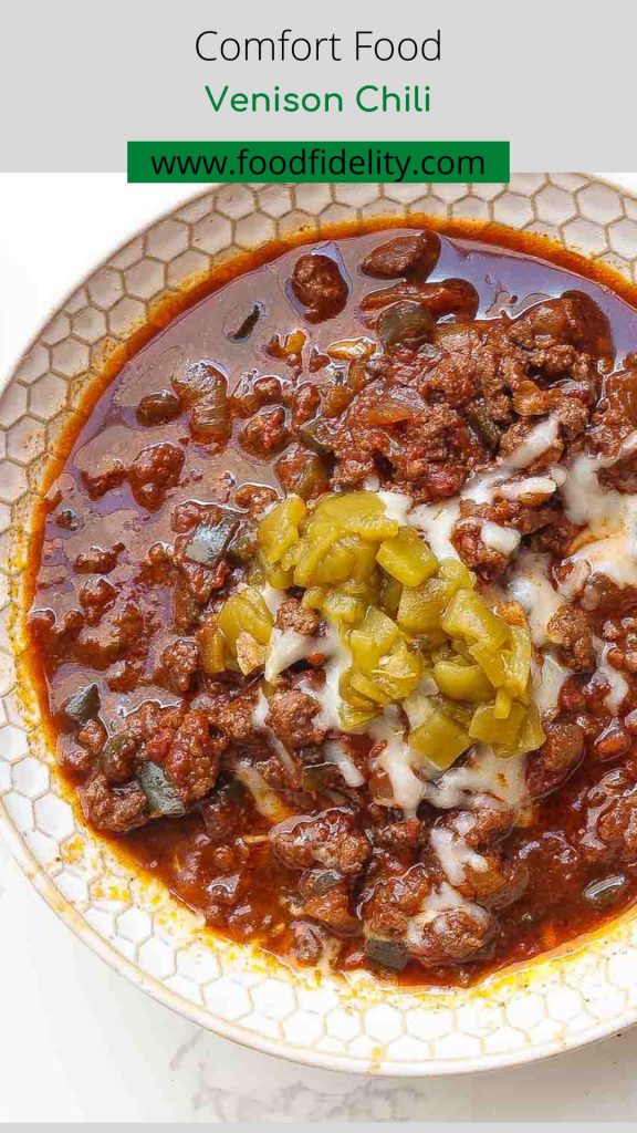 venison chili in a white bowl topped with cheese and green peppers