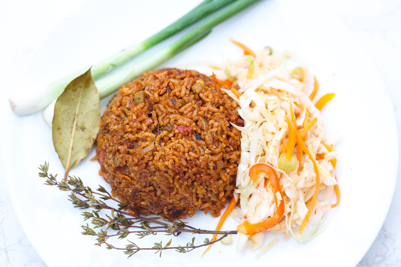 red rice on white plate with green onions and haitian pikliz