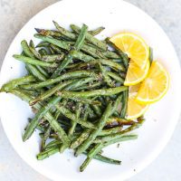 air fried green beans on a white plate with lemon slices