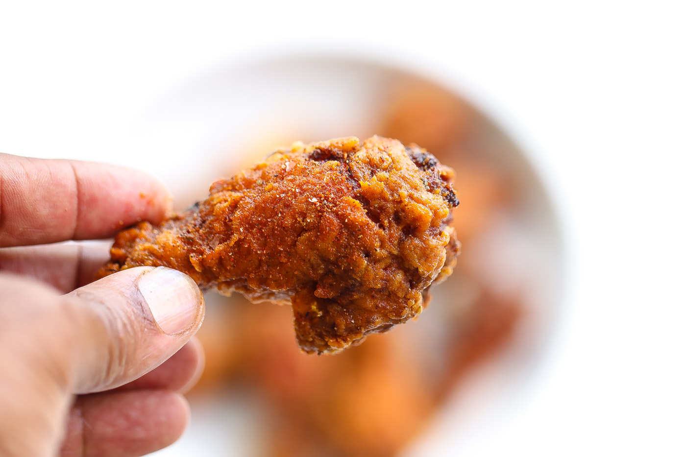 deep fried chicken wing held by fingertips