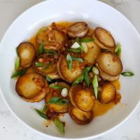 vegan mushroom scallops in white bowl topped with green onions