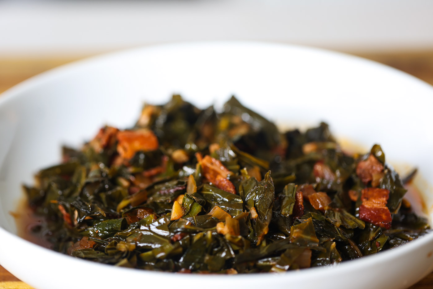 braised collard greens with bacon in a white bowl