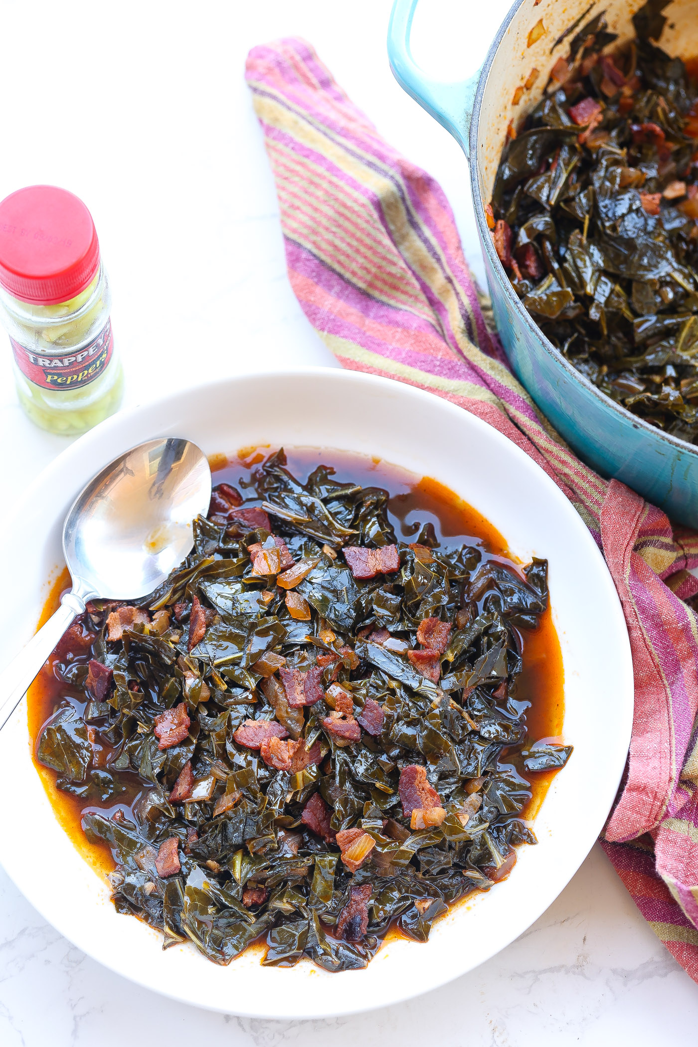 braised collard greens with bacon in a white bowl