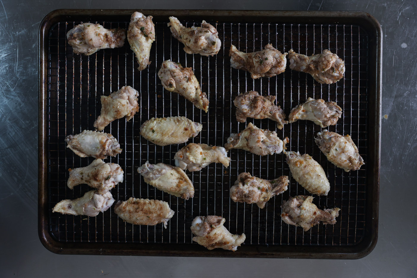 raw seasoned wings on a baking tray