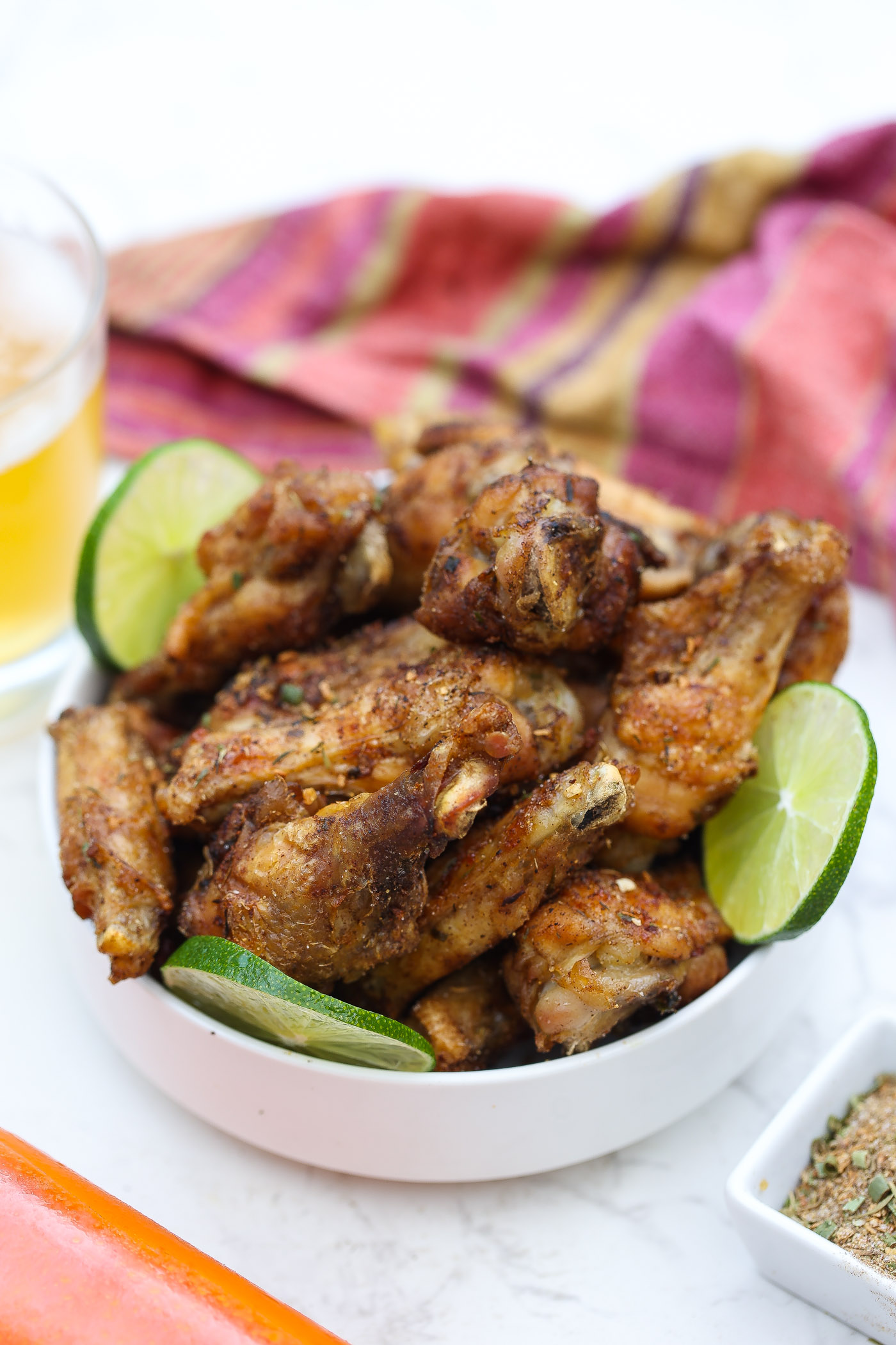 baked jerk wings in a bowl with sliced limes