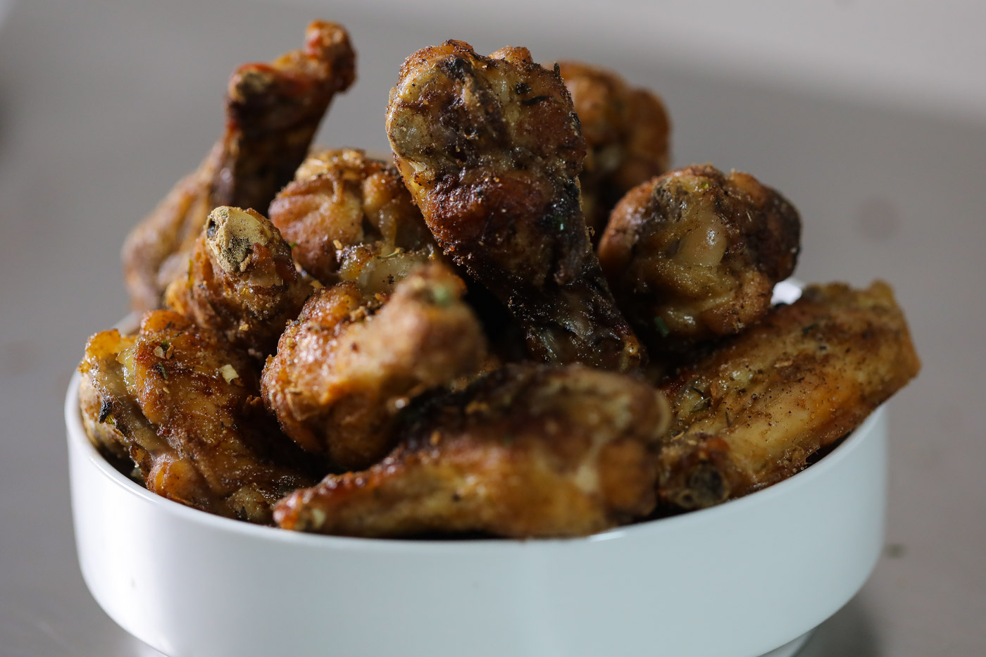 baked jerk wings in a bowl with sliced limes