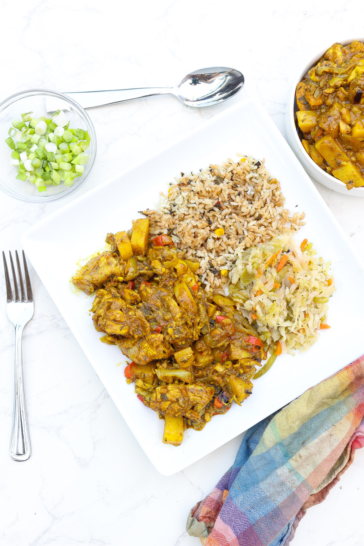 jamaican curry chicken on plate with cabbage and rice.