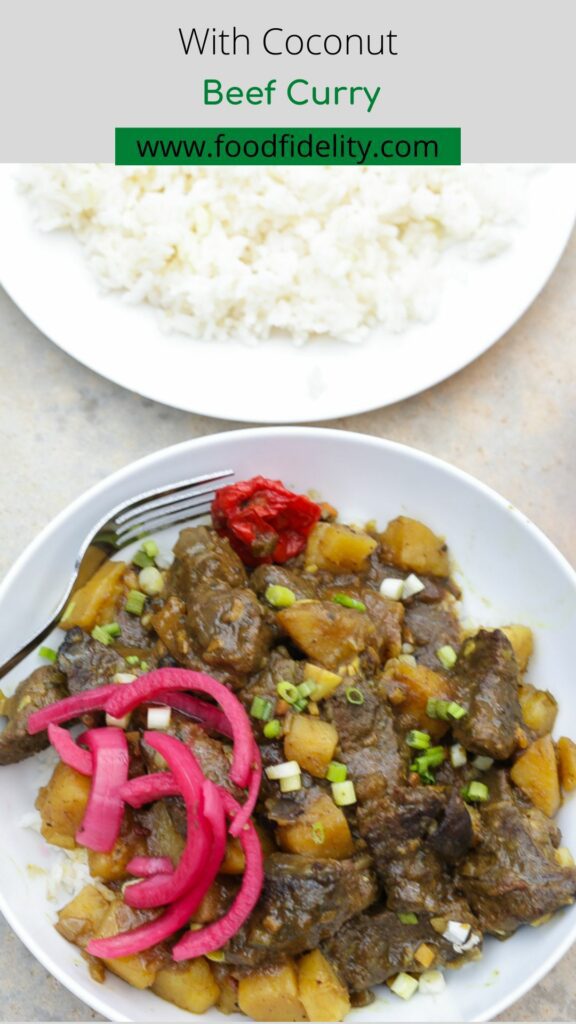 coconut beef curry with potatoes on white plate with pickled red onions