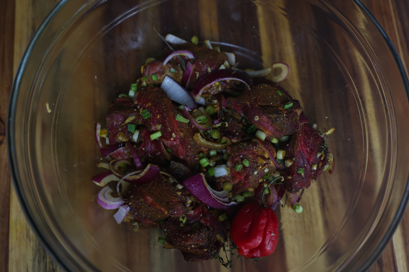 raw beef marinating in a clear glass bowl
