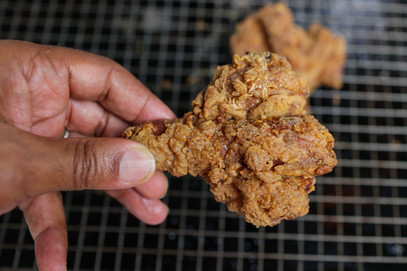 butterflied fried chicken drumstick in hand