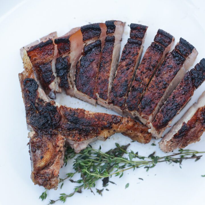 sliced reverse seared pork chop on white plate