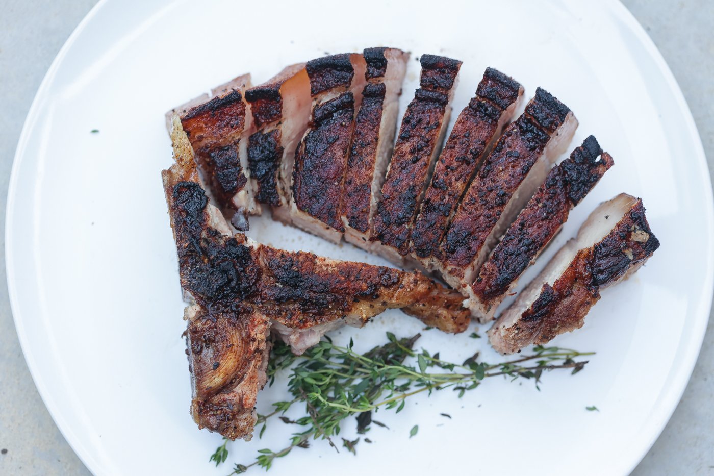 sliced reverse seared pork chop on white plate