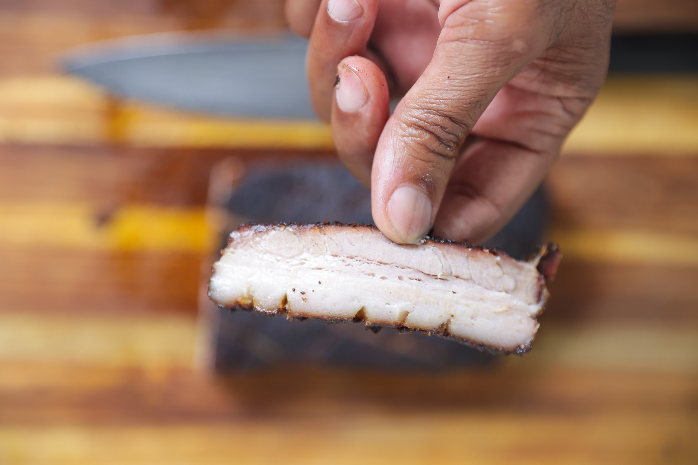 smoked pork belly sliced on wooden cutting board