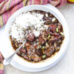 chicken and sausage gumbo with rice in white bowl.