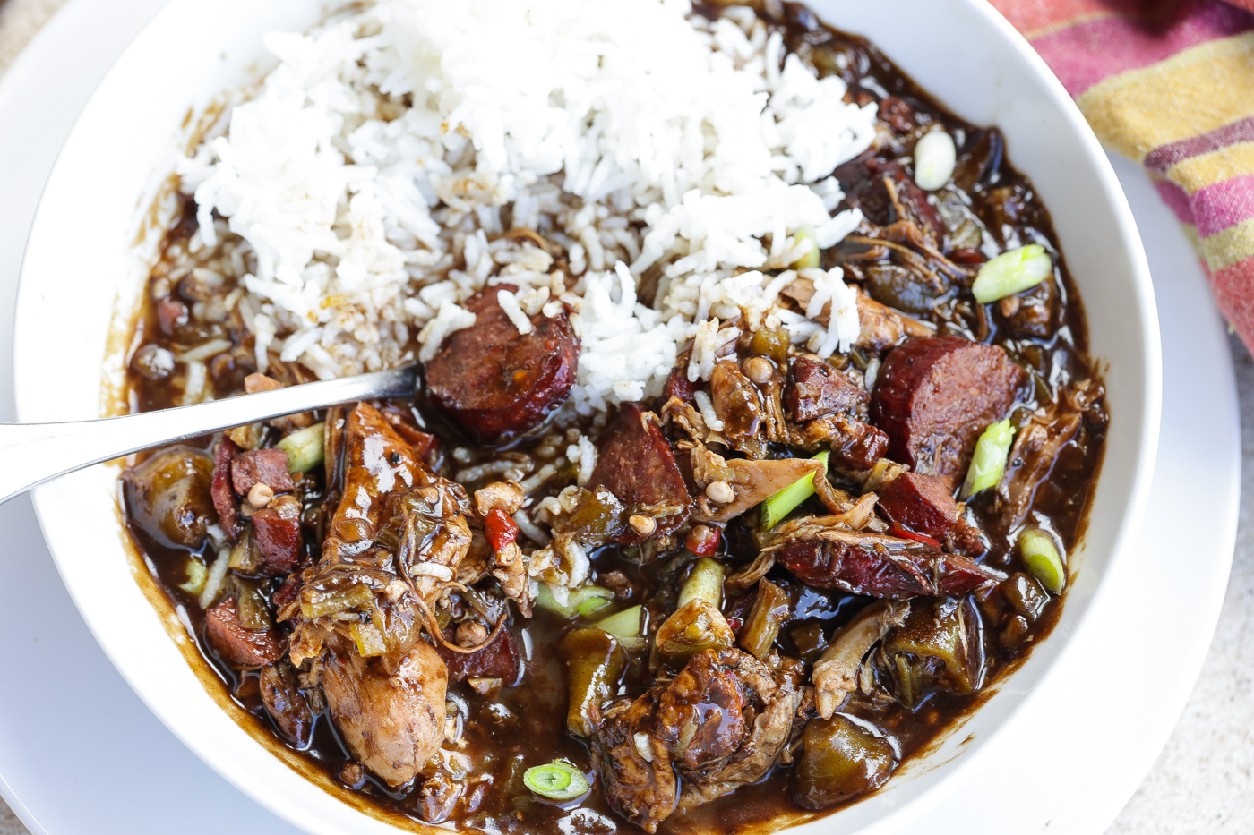 chicken and sausage gumbo with rice in white bowl.