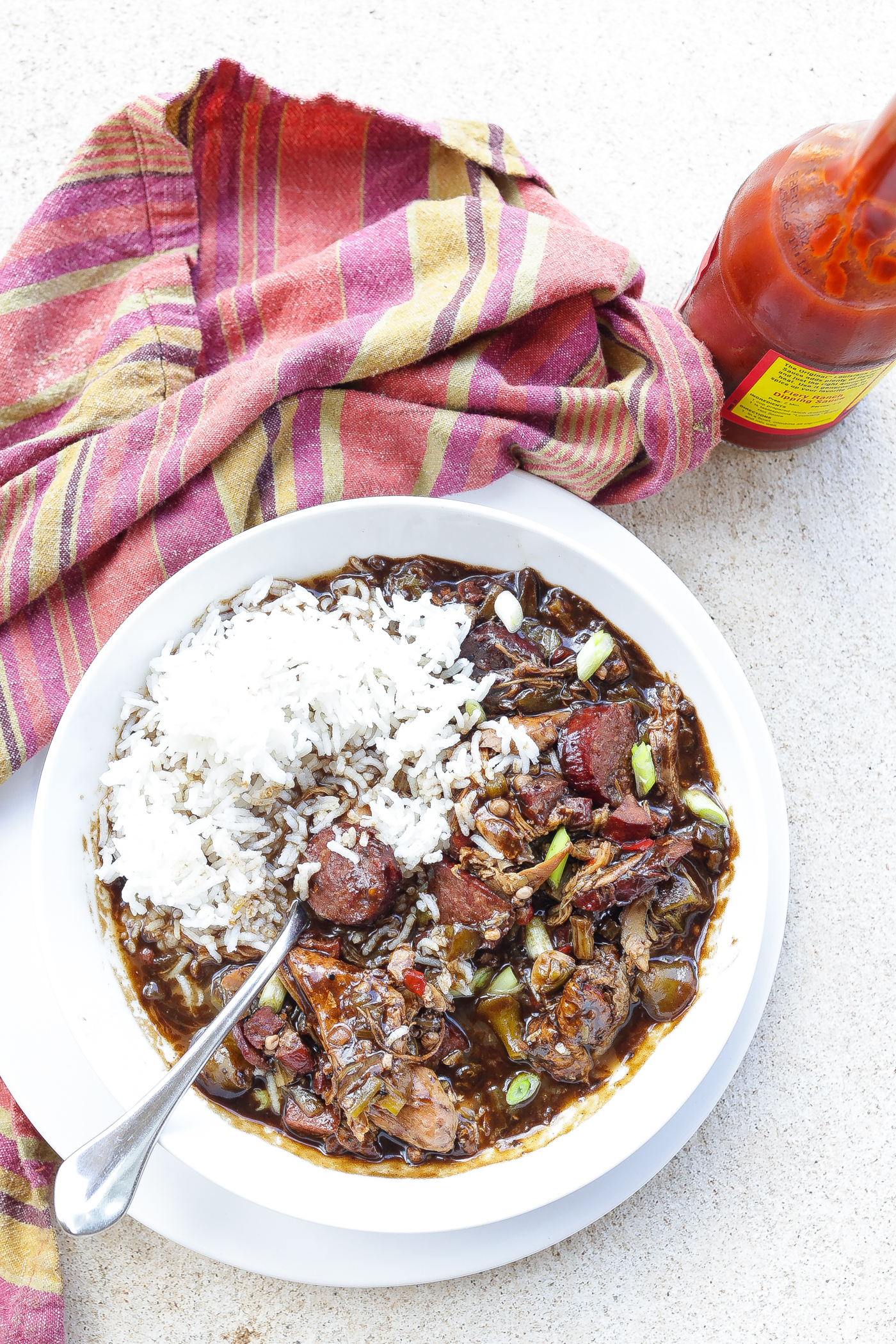 chicken and sausage gumbo with rice in white bowl.