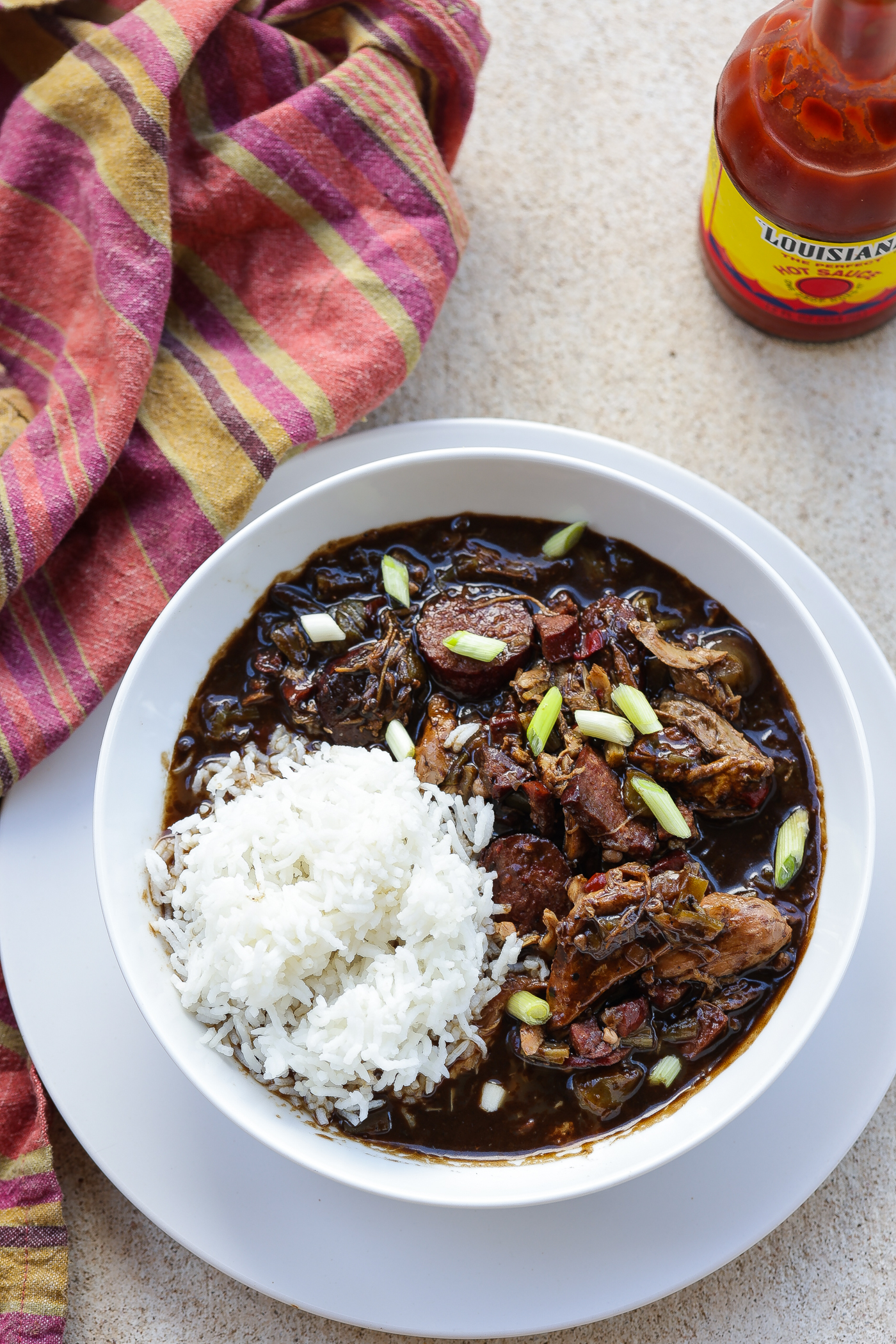 chicken and sausage gumbo with rice in white bowl.