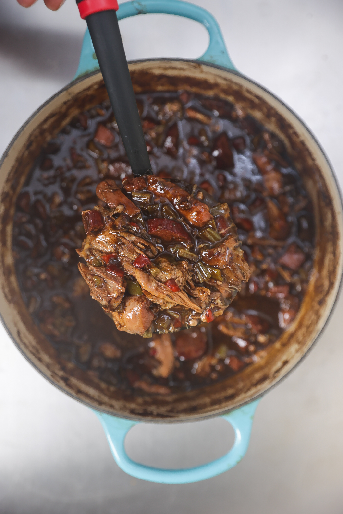 spoonful of chicken and sausage gumbo in a blue pot