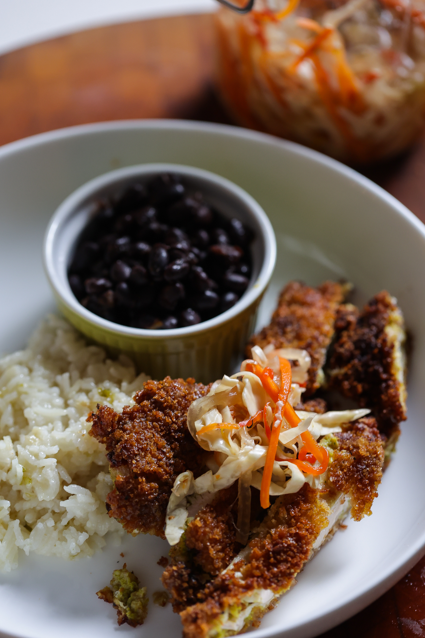 fried chicken katsu on white plate with rice and black beans