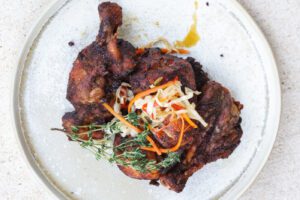 haitian fried chicken on a white plate topped with pickled slaw