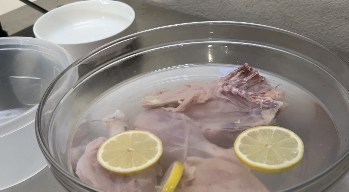 raw chicken in bowl of water with lemons
