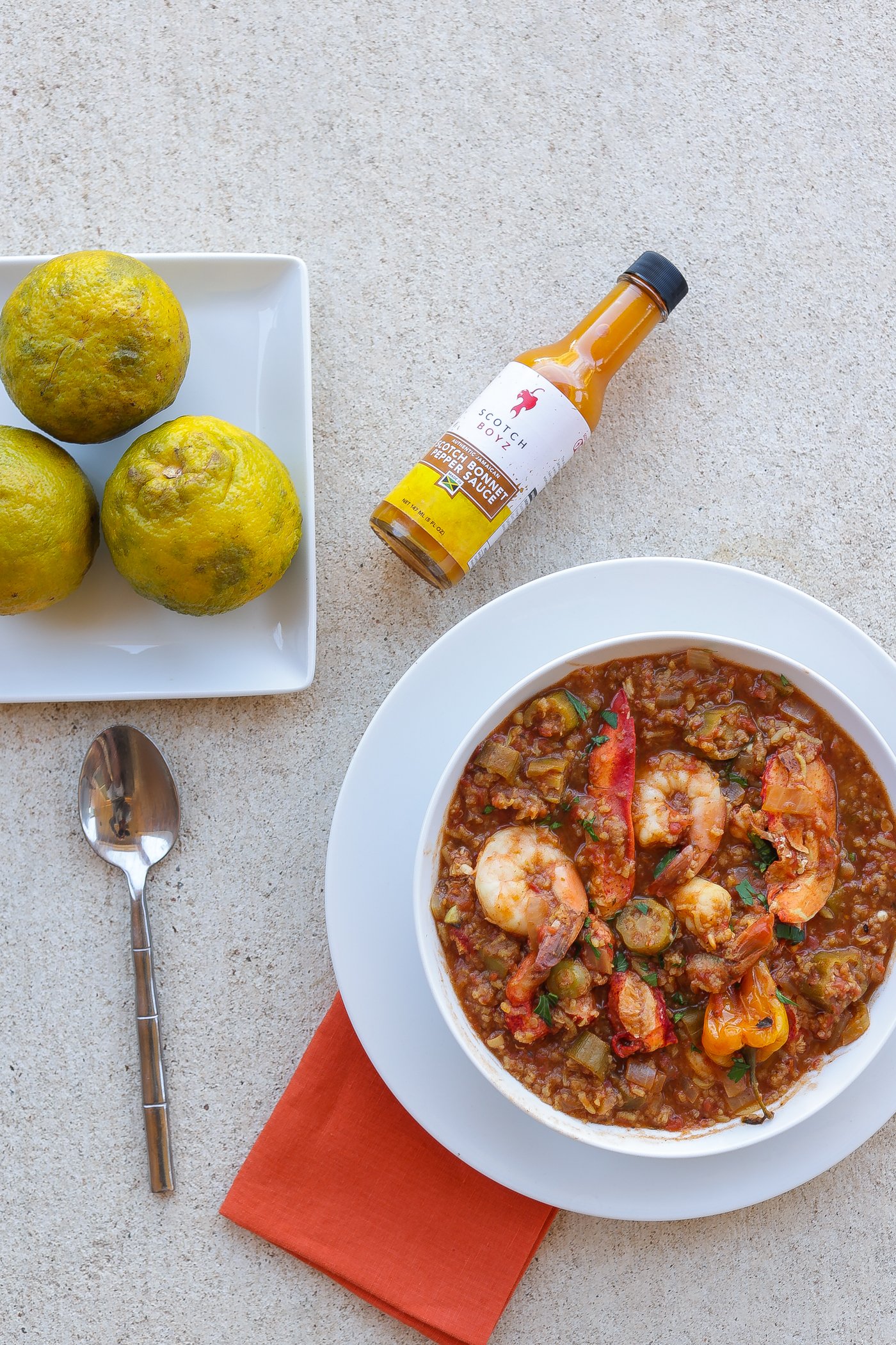 lobster and rice stew with shrimp and okra in white bowl with sour oranges