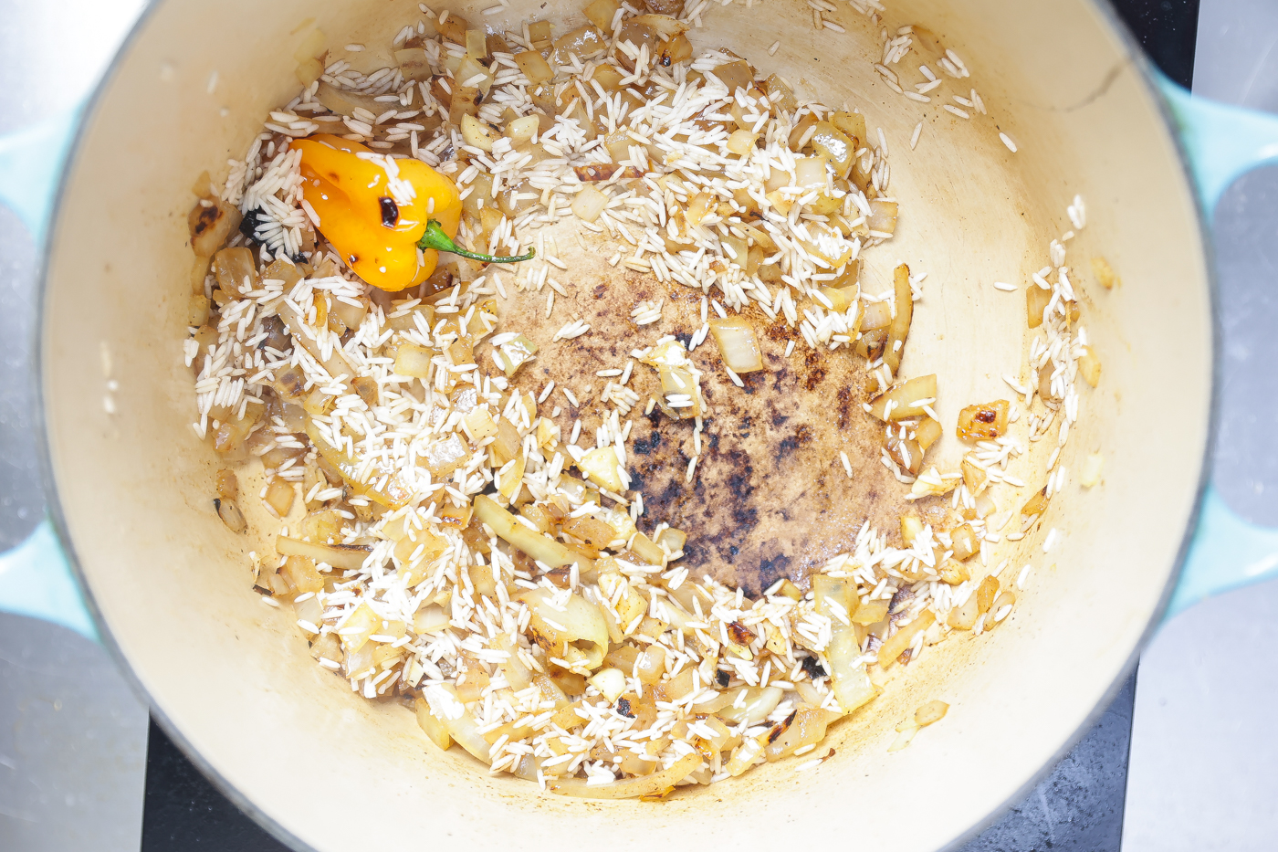 onions sauteing in a pot with a yellow pepper