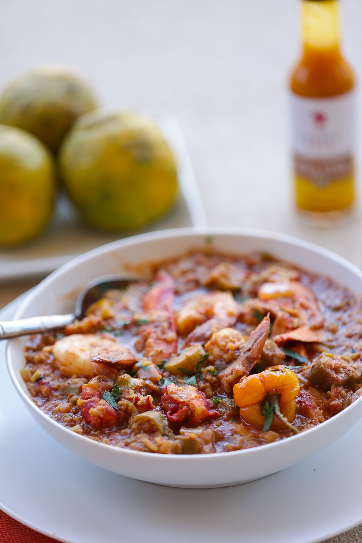lobster and rice stew with shrimp and okra in white bowl with sour oranges