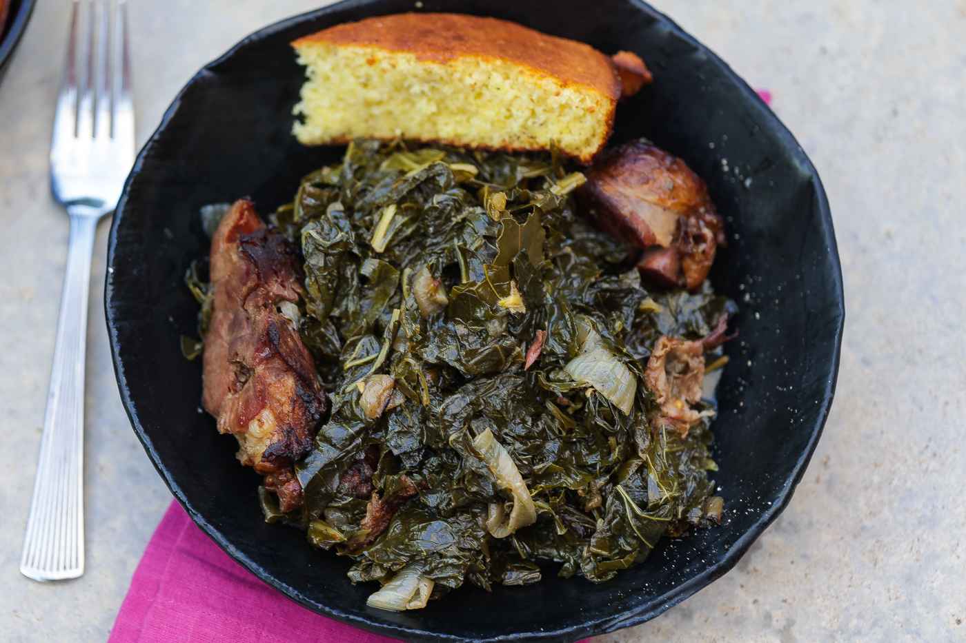 mess o greens in black bowl with cornbread