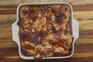 southern bread pudding topped with sauce in white pan