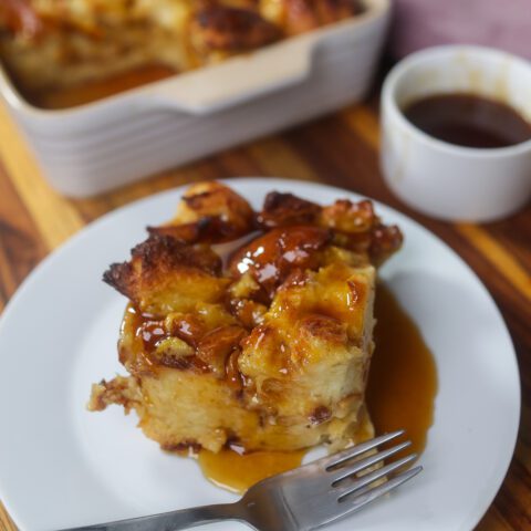 southern bread pudding topped with sauce in white pan