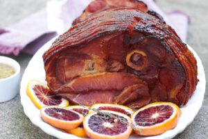 A sliced maple glazed ham placed on a white platter.