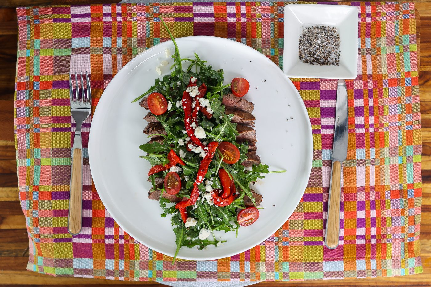 flank steak and arugula salad on a white plate