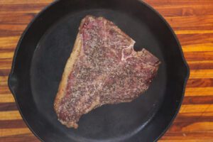 porterhouse steak cooking in cast iron skillet