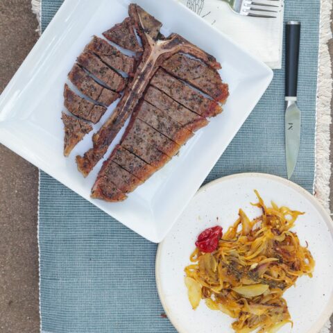 sliced porterhouse steak on white plate with yassa onions