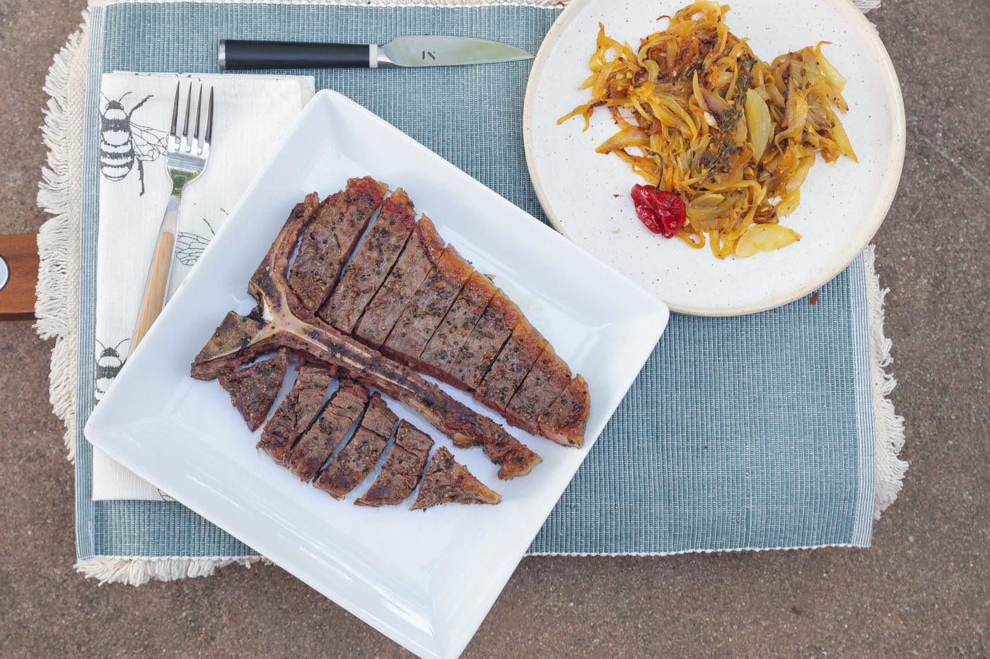 sliced porterhouse steak on white plate with yassa onions