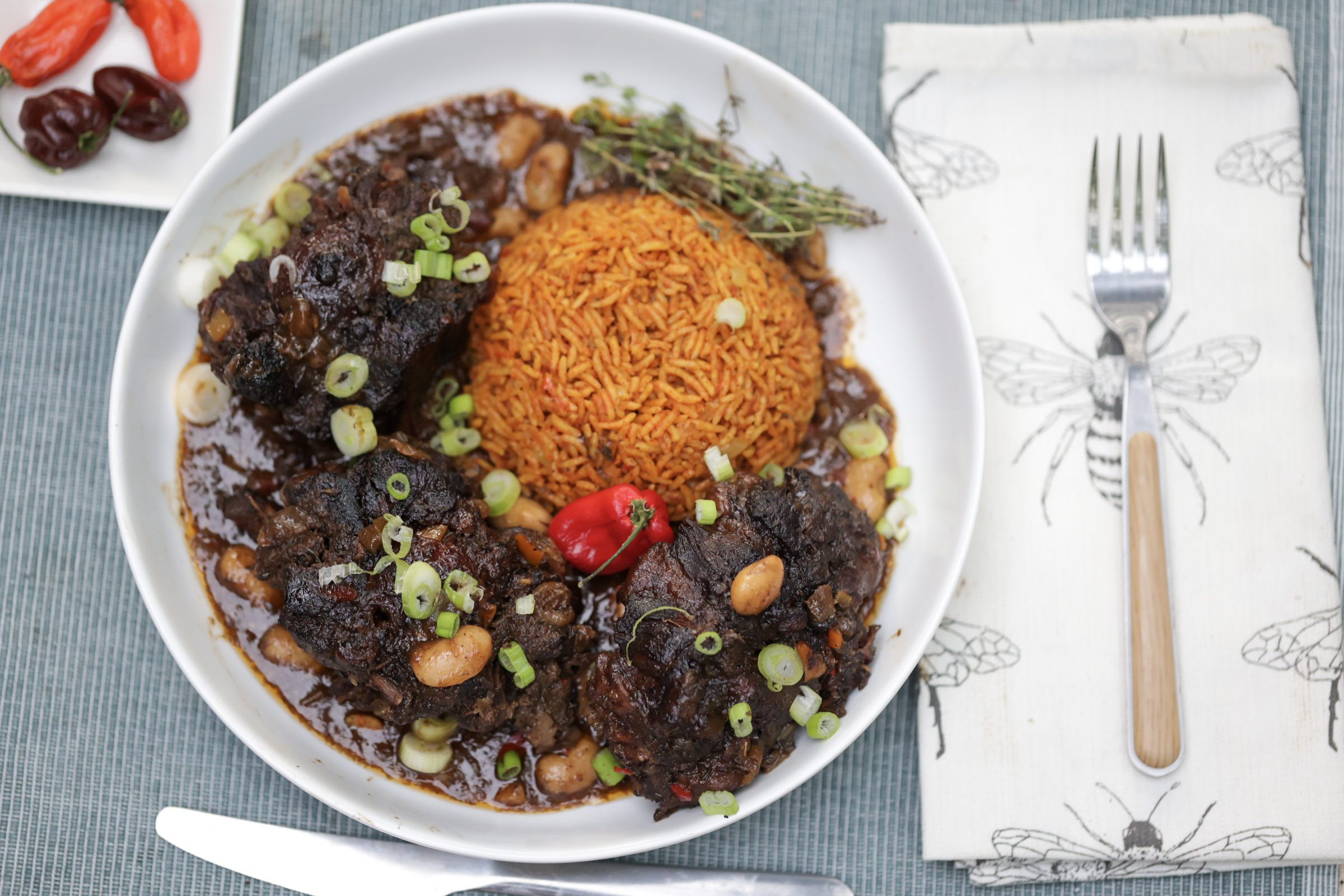 jamaican oxtail with butter beans and jollof rice in white bowl