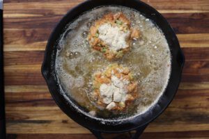 salmon croquette patties frying in skillet
