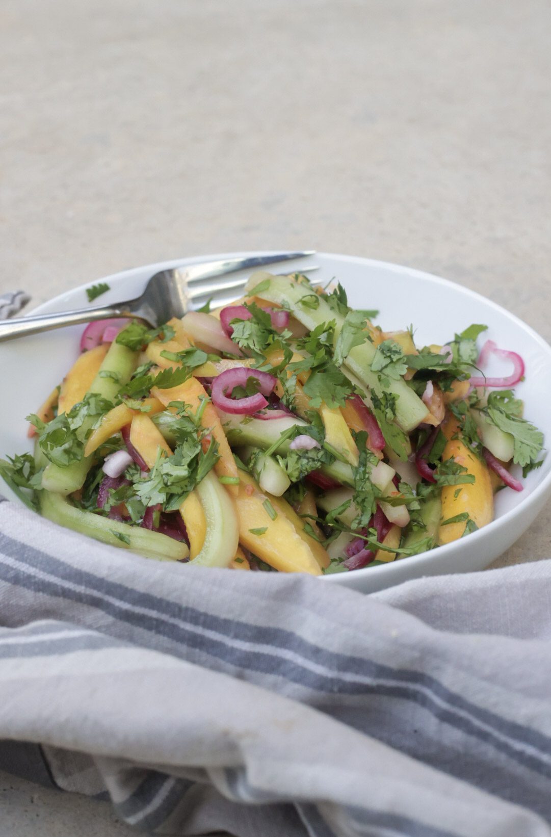 salad with cucumber and mangos in a white bowl