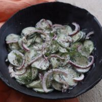 creamy cucumber salad with dill in a black bowl