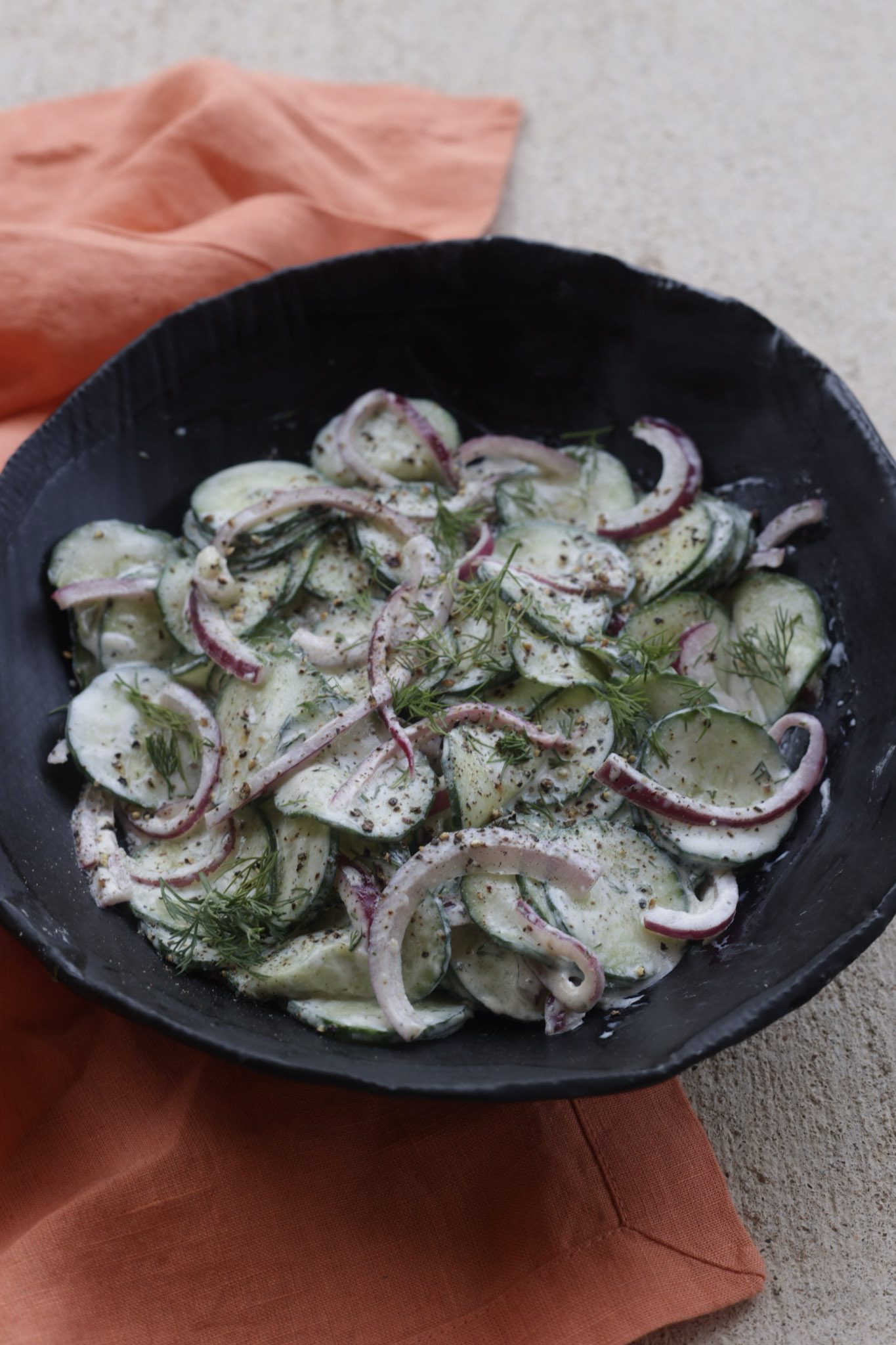 creamy cucumber salad with dill in a black bowl