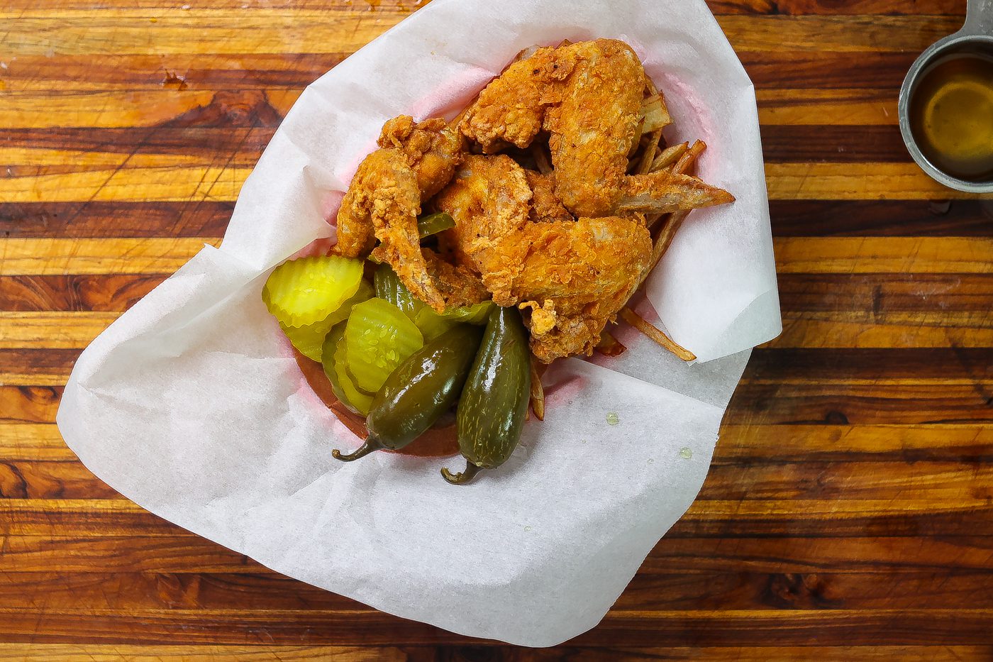 fried chicken wings in a basket with peppers and pickles
