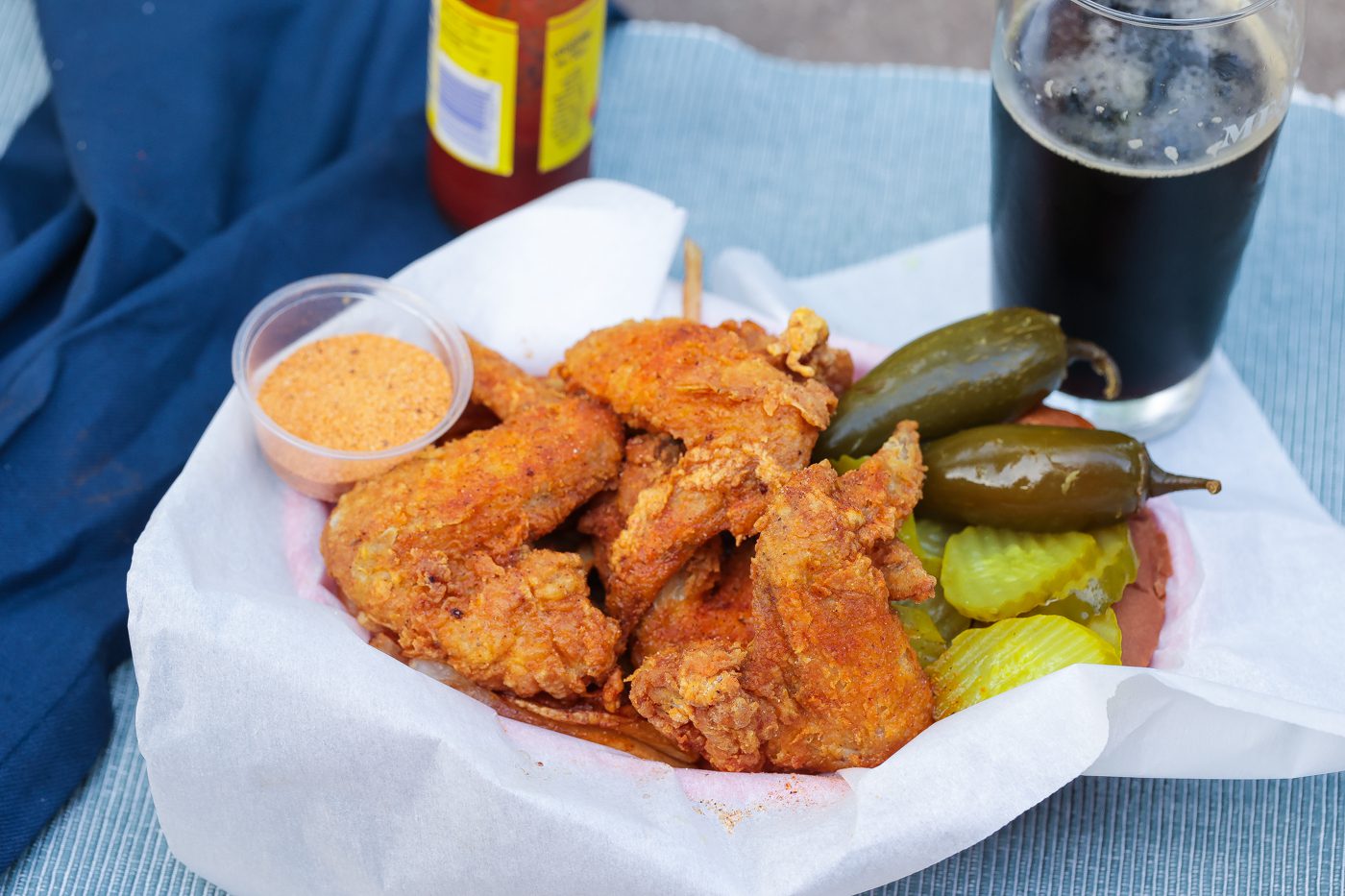 fried chicken wings in a basket with peppers and pickles