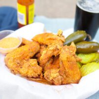 fried chicken wings in a basket with peppers and pickles