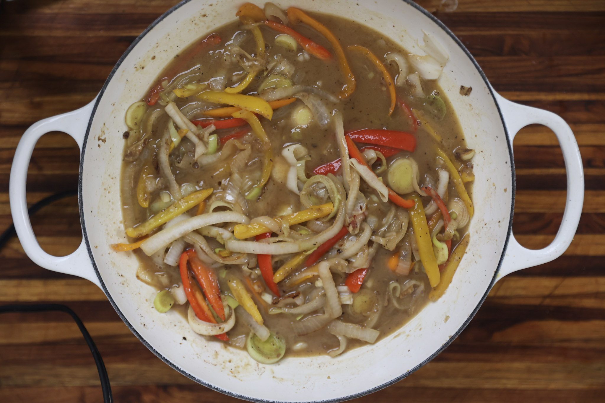 onions and peppers cooking in cider broth