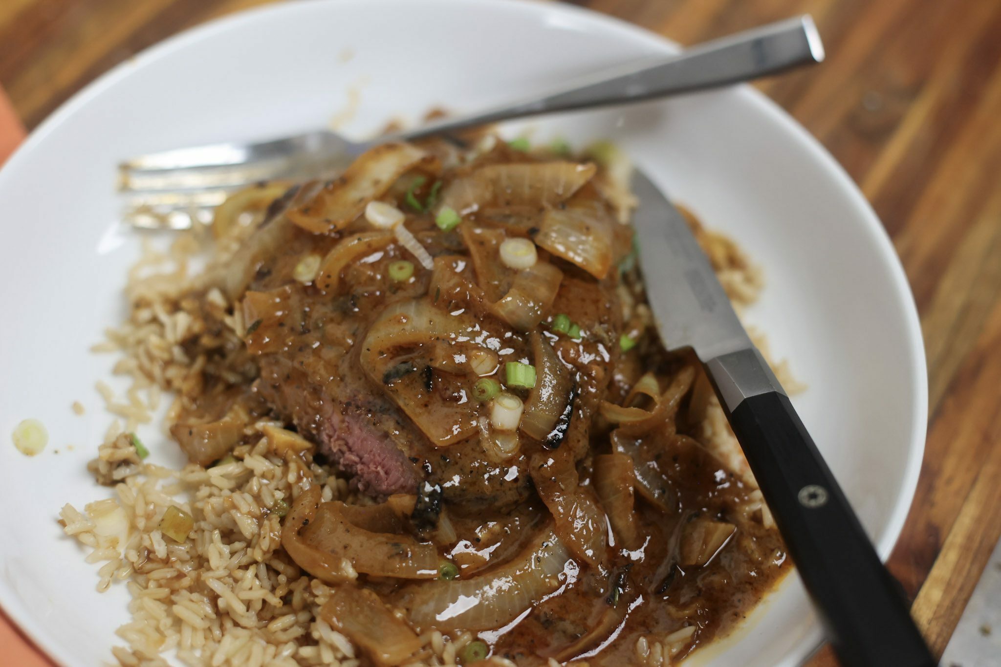 smothered steak and onion gravy with rice in white bowl
